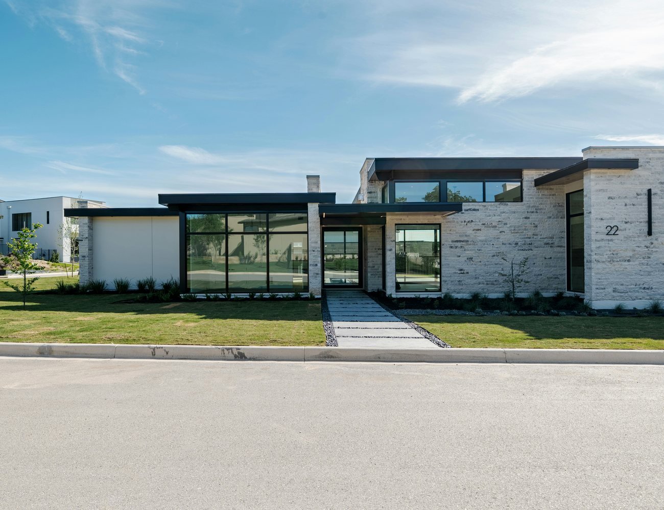 Professionally photographed contemporary single-storey home with a clean stone facade, broad lawn and inviting entrance, representing a well-presented property listing.