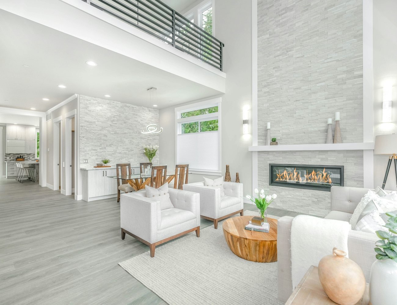Bright professionally photographed open-plan living room with white seating, a fireplace and large windows, illustrating the kind of rental space a seeker can discover.