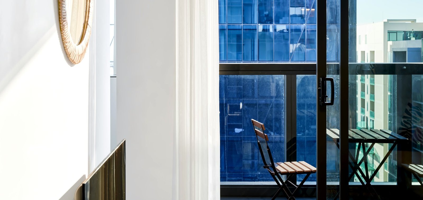 Professionally photographed apartment interior beside a city-facing balcony, representing practical guidance for people navigating a rental decision.