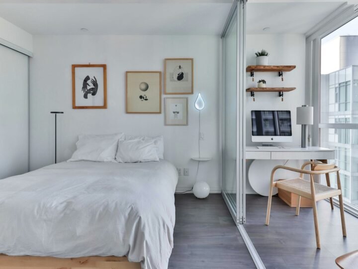 Professional photograph of a neat self-contained bedroom with a bed, desk, shelving and balcony light; representative demo image for the Pedu room Gallery image 2 of 5 for Affordable Student Apartment in Kwadaso.