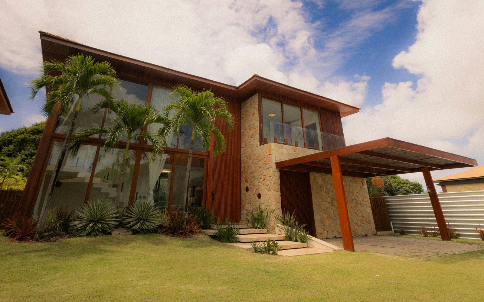 Professional exterior photograph of a spacious contemporary two-storey house with lawn, palms and a covered driveway; representative demo image for the Lakeside family house Gallery image 1 of 5 for Spacious 3-Bedroom Family House at Lakeside Estate.