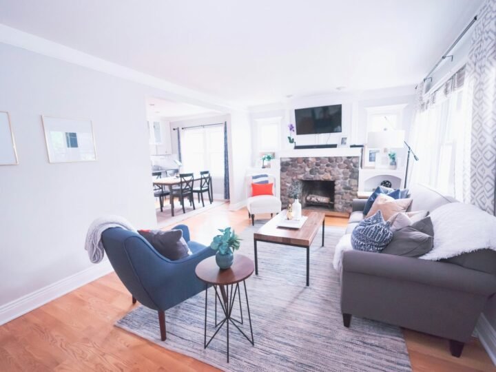 Professional photograph of a renovated living room with grey seating, pale walls and an adjoining dining area; representative demo image for the Ahodwo chamber-and-hall unit Gallery image 5 of 5 for Gated 3-Bedroom Home in Tema Community 25.